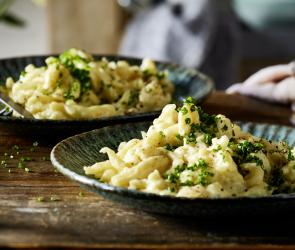 Käsespätzle angerichtet auf einem rustikal gedeckten Tisch