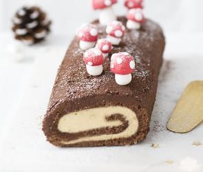 Schokoladen-Biskuitrolle mit kleinen Pilzen dekoriert.