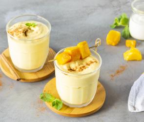 Frozen-Mango-Lassi serviert in zwei Gläsern auf Holzuntersetzern.