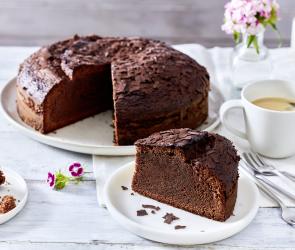 Einfacher Schokokuchen mit einem angeschnittenen Stück auf einer Kaffeetafel.