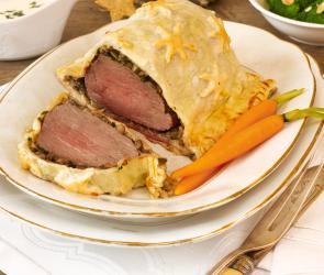 Beef Wellington auf einem gedeckten Tisch, eine Scheibe angeschitten.