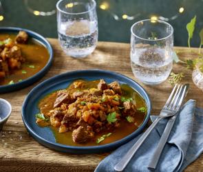 Entenragout auf einem blauen Teller angerichtet, Lichterkette im Hintergrund