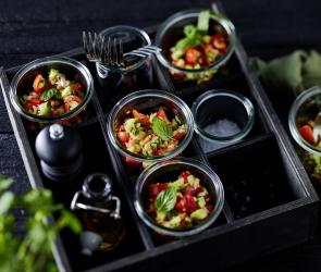 Tomaten Gurken Salat in kleinen Gläsern abgefüllt serviert.