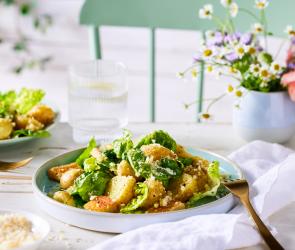 Caesar salad in Schüsseln auf einem gedeckten Tisch mit Blumen.