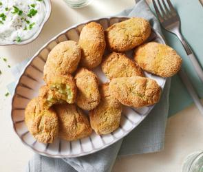 Kroketten mit Zucchini auf einem Teller mit Dip.