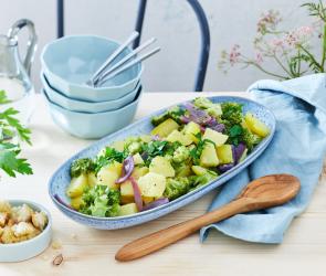 Kartoffelsalat mit Gemüse auf einem Servierteller.