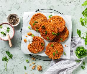 Gemüsepuffer auf einem Gitter, daneben eine Schale mit Kräuterdip