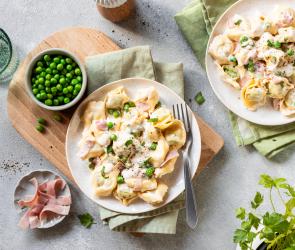 Tortellini mit Schinken und Erbsen auf Teller