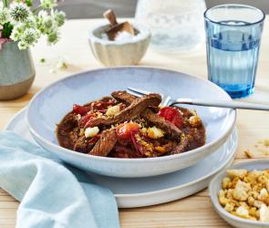 Streakstreifen mit Tomate in einem tiefen Teller angerichtet.
