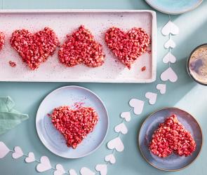 Kleine rote Herzen aus Himbeeren und Marshmallows auf einer rosa Servierplatte