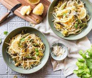 Spaghetti mit Zitronen und grünem Spargel in zwei tiefen Tellern.