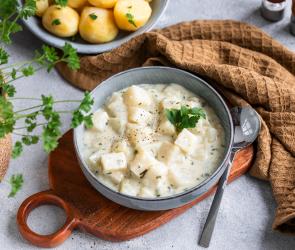 Rahmkohlrabi in einer Schale dazu Kartoffeln und Petersilie.