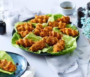 Vegane Cig Köfte in Salatblättern auf einem Teller.