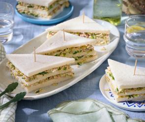 Tramezzini mit Thunfisch mit Holzspießen auf einem Servierteller.