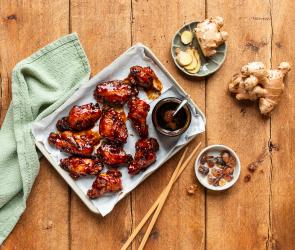 Chicken Wings süß-sauer auf einem Tablett mit Sauce.