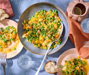 Erbsensalat in einem tiefen Teller mit einem großen Löffel.