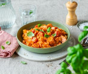 Tiefer Teller mit Pasta, Lachs und Tomaten.