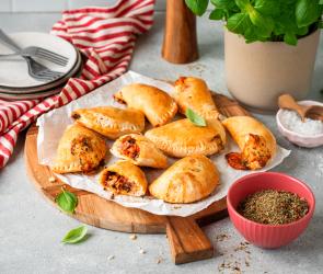 Mini-Calzone mit Schinken und Champignons auf einem gedeckten Tisch.