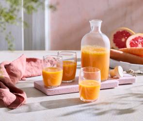 Karotten-Zitrus-Shot in einer Karaffe und Gläsern.