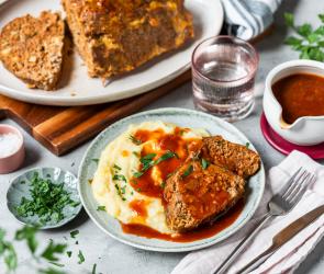Hackbraten mit Sauce und Kartoffelpüree auf einem Teller und Braten im Ganzen.