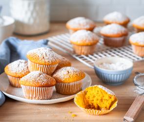 Kürbis-Muffins auf einem Kuchengitter mit Puderzucker bestäubt.