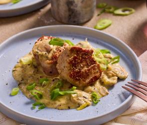 Schweinemedaillons mit Champignonsauce auf flachen Tellern angerichtet.