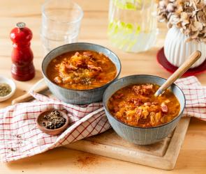 Sauerkrautsuppe mit Speck in Schüsseln mit rustikalem Tuch.