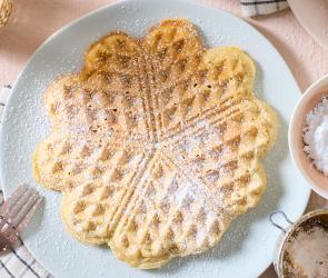 Vegane Herzwaffel mit Puderzucker auf einem Teller.