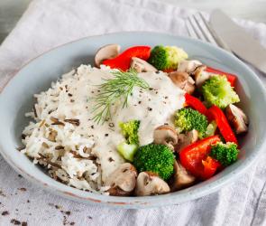 Wildreis mit Gemüse und Forellen-Frischkäse-Sauce auf einem Teller.