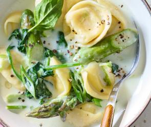 Tortellini-Suppe mit grünem Spargel in einer Schüssel.
