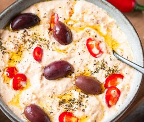 Chtipiti (Griechische Schafskäsecreme) mit Oliven in einer Schale.