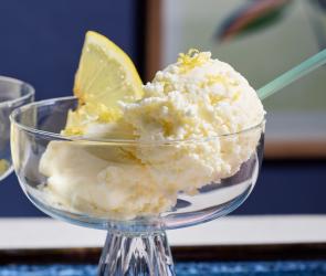 Zitroneneis in Glasschälchen mit frischen Zitronenscheiben garniert.