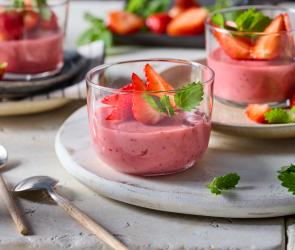Erdbeerpudding mit frischen Erdbeeren und Minze garniert in Glasschälchen angerichtet.