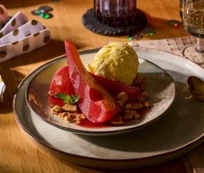 In Rotwein eingekochte Birnen mit weihnachtlichen Gewürzen wie Zimt und Sternanis mit einer Kugel Vanilleeis auf dem Teller.