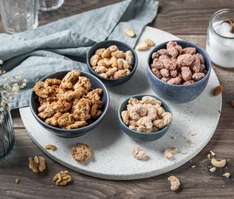 Vier verschiedene gebrannte Nüsse in Schälchen.