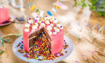 Piñata-Torte angeschnitten mit bunten Schokolinsen in der Mitte.