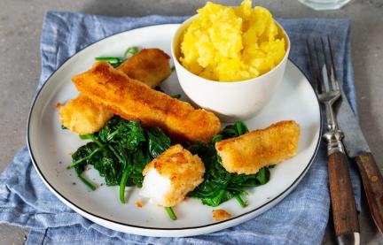 Fischstäbchen, Spinat und Kartoffelpüree auf Teller mit Wasserglas und Besteck
