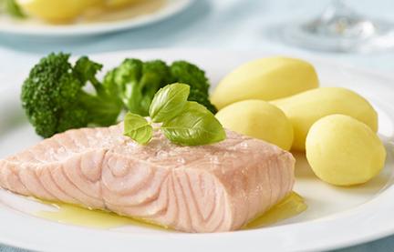 Lachsfilet gedämpft mit Brokkoli und Kartoffeln auf einem Teller.