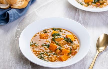 Süßkartoffel- und Kichererbsen-Curry mit Spinat auf Tellern.