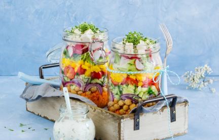 Bunter Schichtsalat mit Kichererbsen und Joghurtdressing im Glas geschichtet.