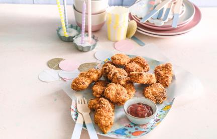 Chicken Nuggets auf einem Teller vor Partydekoration.