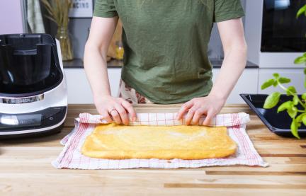 Biskuitteig wird in ein Handtuch gewickelt.