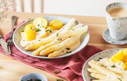 Spargel mit Kartoffeln und Sauce Hollandaise auf einem Teller.