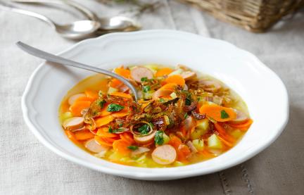 Karotteneintopf mit gerösteten Zwiebeln auf einem gedeckten Tisch.