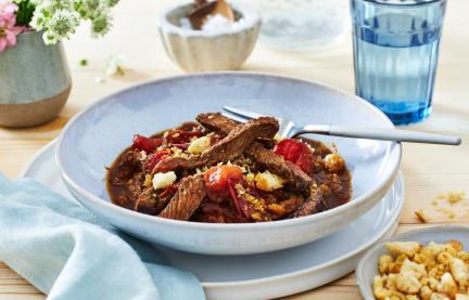Streakstreifen mit Tomate in einem tiefen Teller angerichtet.