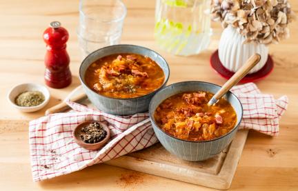 Sauerkrautsuppe mit Speck in Schüsseln mit rustikalem Tuch.