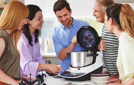 Fünf Personen stehen um die Küchenzeile und schauen sich den Cookit an. 