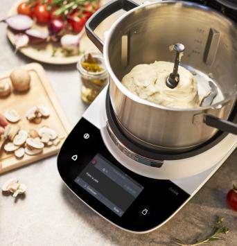 Cookit auf dem Tisch mit frisch geknetetem Teig im Topf. 