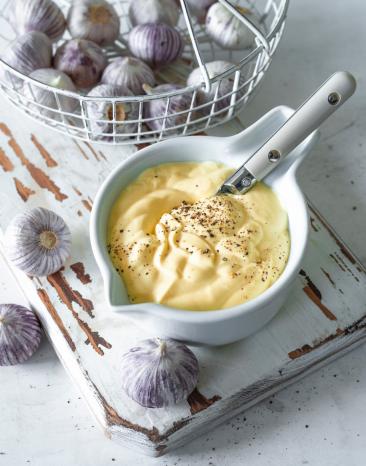 Schüsselchen mit Aioli und Knoblauchzehen im Körbchen.