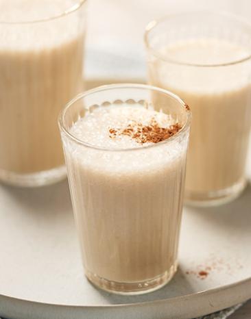 Drei Gläser mit Bananen-Milchshake auf einem Teller.